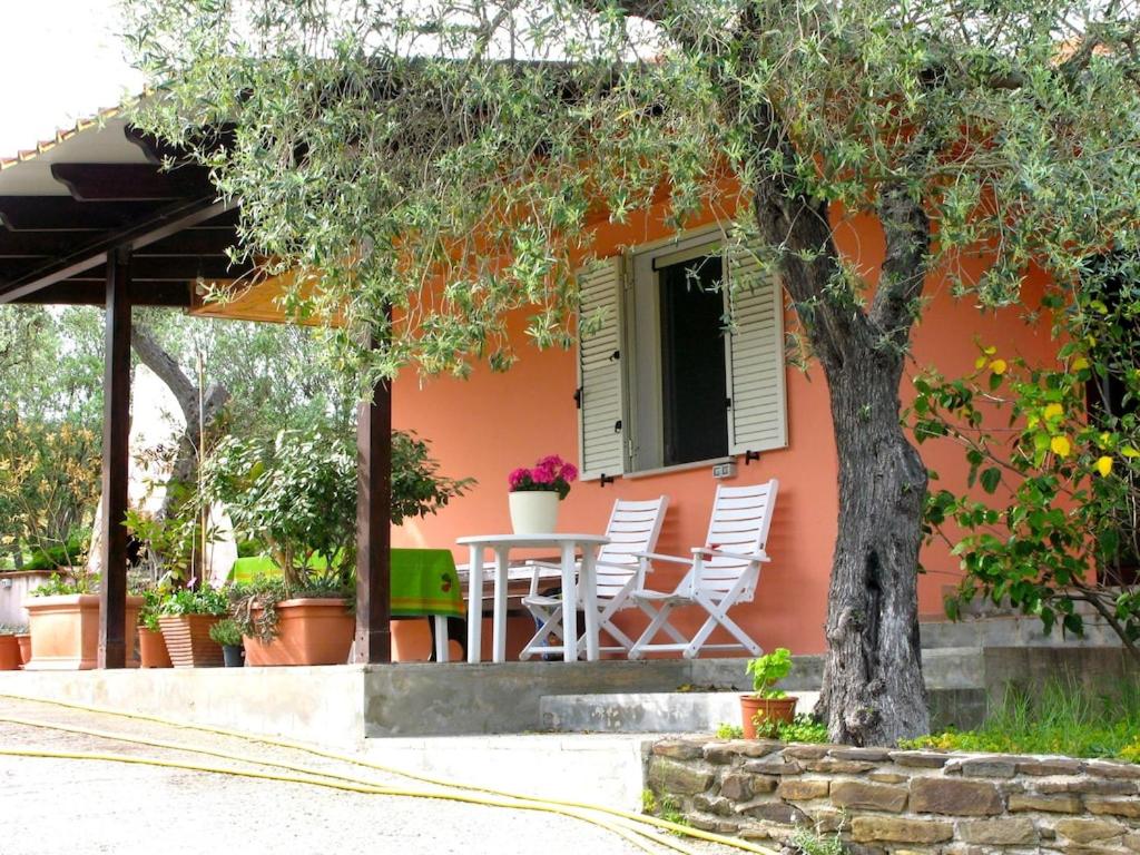 a house with a table and chairs and a tree at Villa Mimosa ad Alghero a 2km dalla spiaggia per 6 persone in Alghero