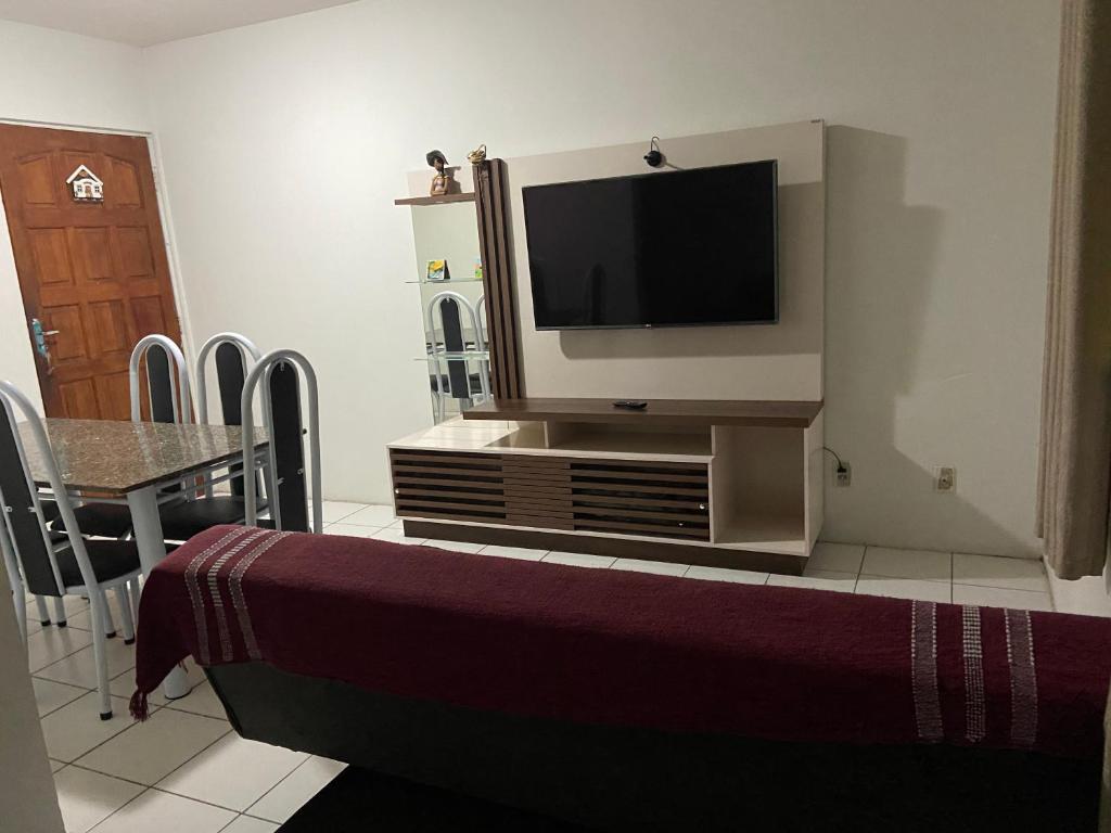 uma sala de estar com uma televisão e uma mesa com cadeiras em Jatiuca 2 em Maceió