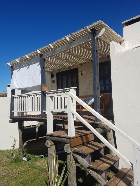 a white house with a porch and a white railing at Ocean Paradise 1 in Punta Del Diablo