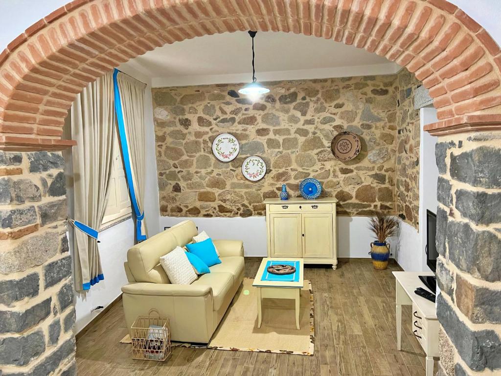 salon z kanapą i kamienną ścianą w obiekcie Sa Domo de Tzia Elene w mieście Irgoli