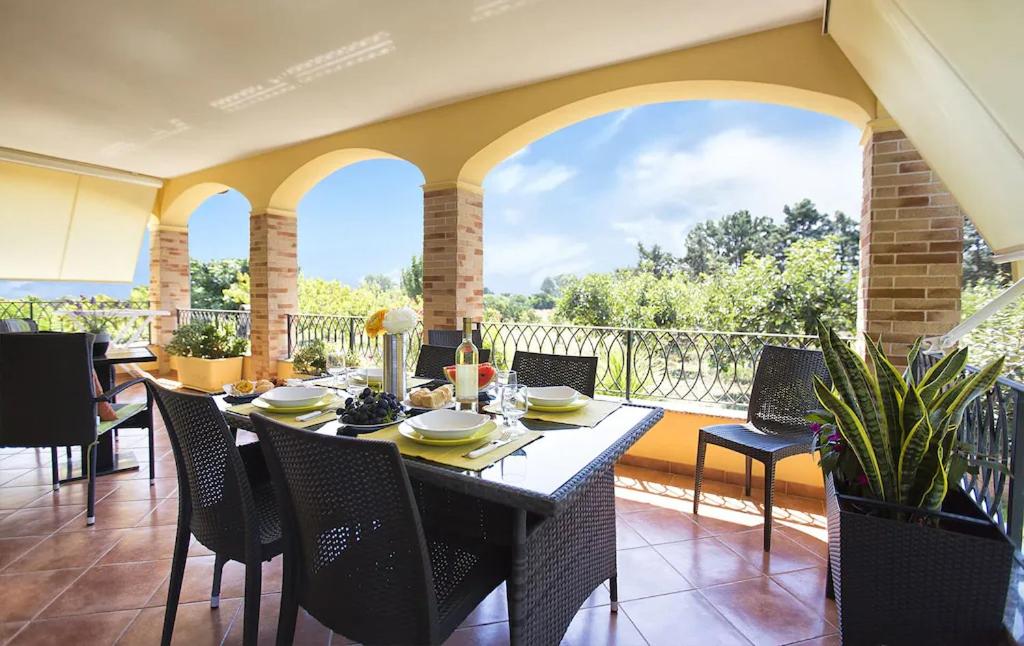 uma sala de jantar com uma mesa e cadeiras numa varanda em Alghero Villa Mistral per 7 persone Terrazza BBQ AC WiFi em Alghero