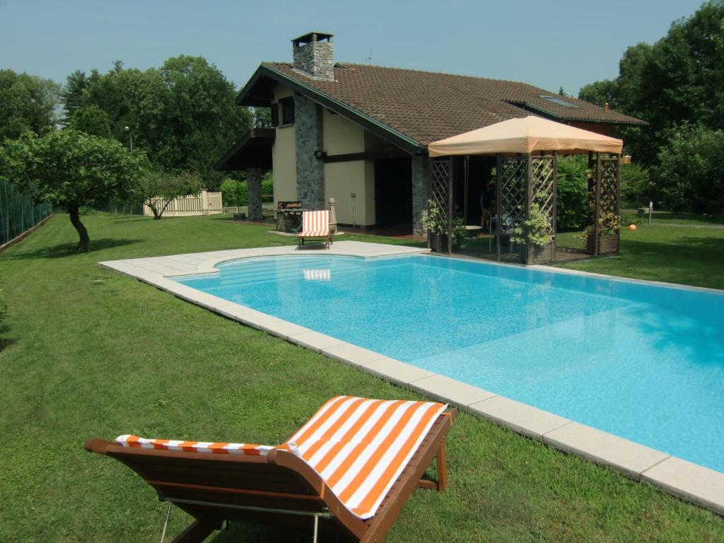 a swimming pool with a chair and an umbrella at B&B Il Ciliegio in Lomnago