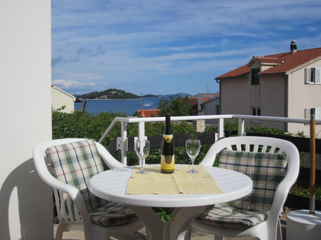 una mesa blanca con 2 copas de vino en el balcón en Apartment Tisno Residence en Tisno