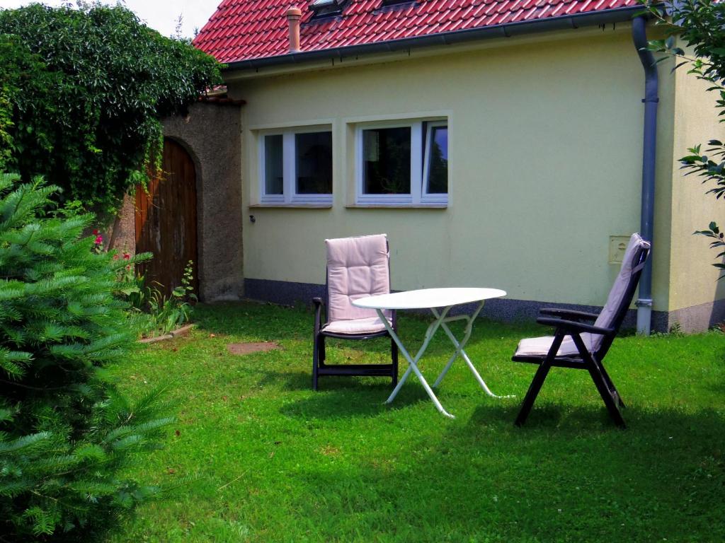 dos sillas y una mesa en el patio de una casa en Ferienwohnung im Blumengarten, en Angermünde