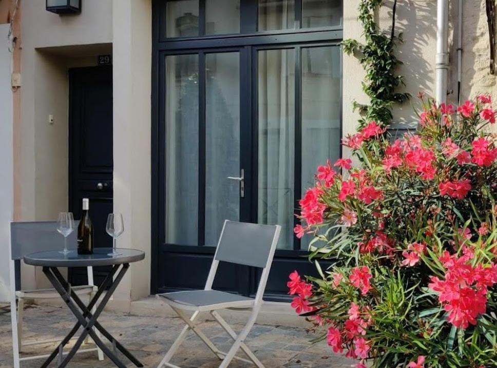 una mesa y una silla en un patio con flores en La maison de Marie, maison de ville 4 personnes, option chambre patio 2 pers supp, en Aigues-Mortes