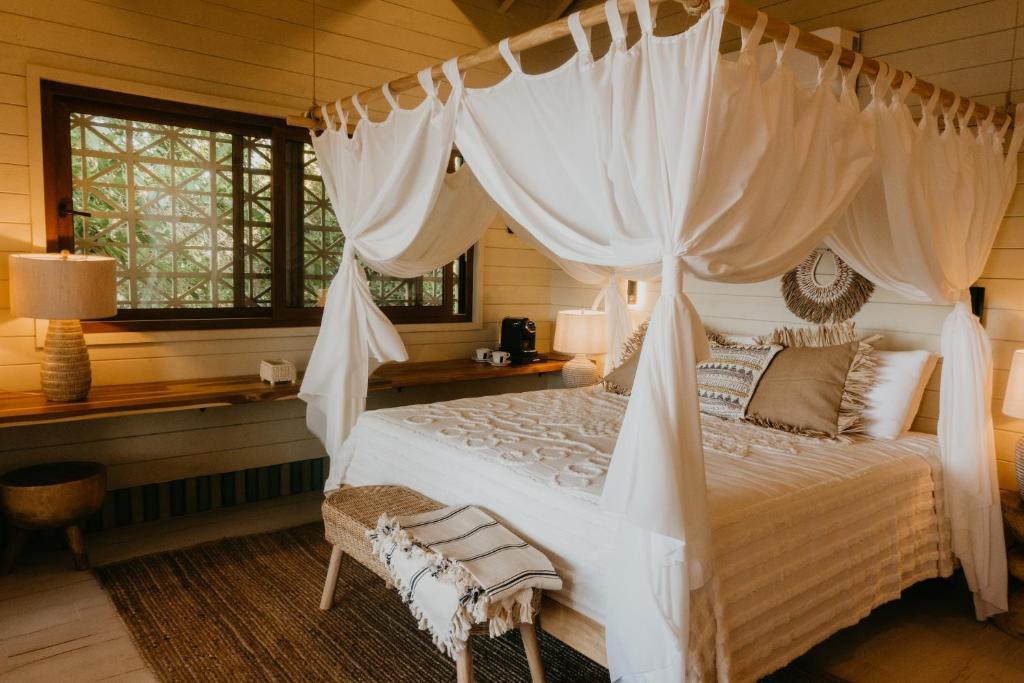 um quarto com uma cama de dossel branca em Tranquilseas Eco Lodge & Dive Center em Sandy Bay