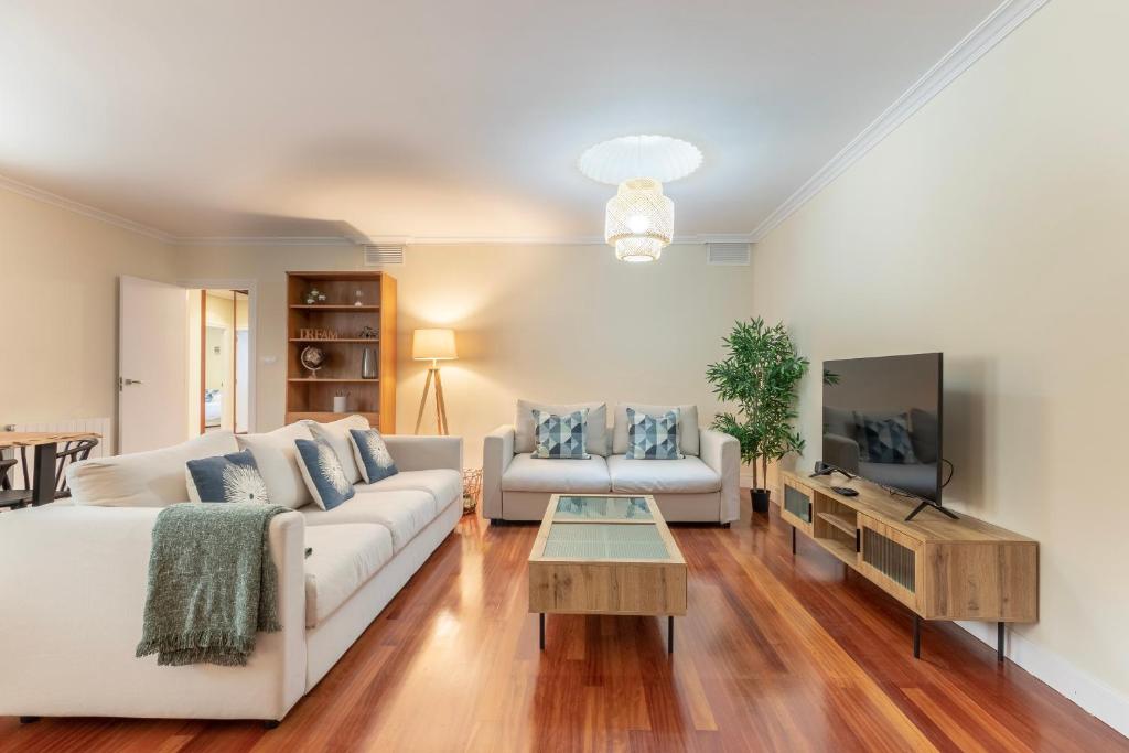 ein Wohnzimmer mit einem weißen Sofa und einem TV in der Unterkunft AkomodaT en apartamento en el centro de Bilbao con parking in Bilbao