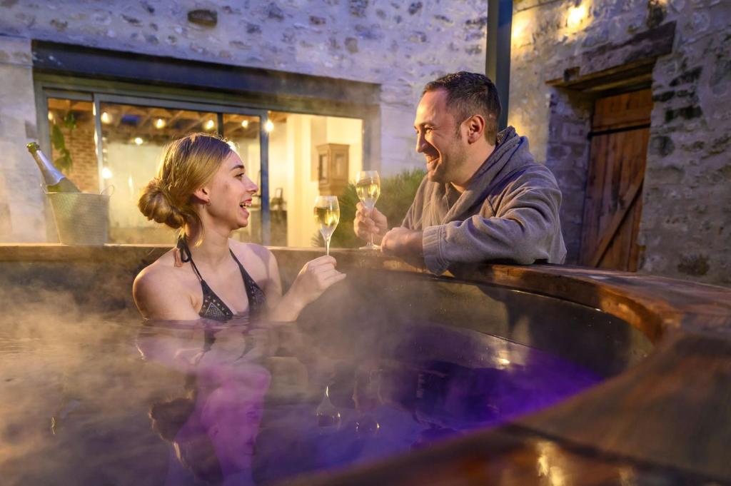 a man and a woman sitting in a hot tub at La Grange in Bruyères-et-Montbérault