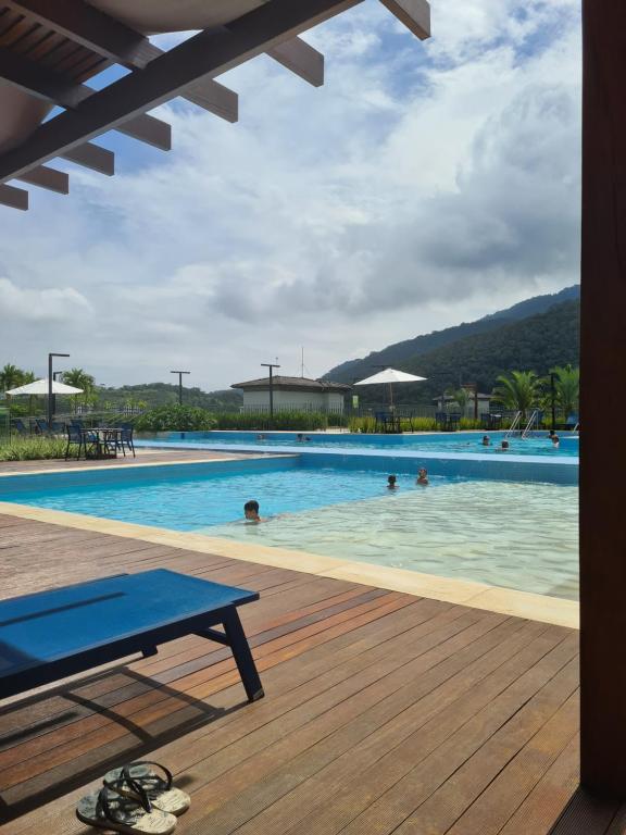 a swimming pool with people in the water at Apartamento Ubatuba Reserva DNA in Ubatuba