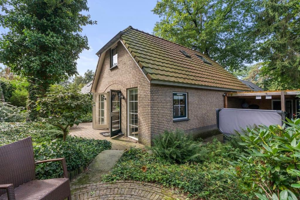 uma pequena casa de tijolos com um jardim em frente em Luxe vakantiehuis in het bos met jacuzzi en sauna em Lunteren
