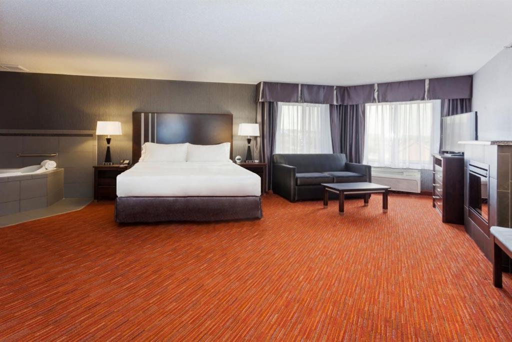 a large hotel room with a bed and a chair at Holiday Inn Express & Suites Rapid City by IHG in Rapid City