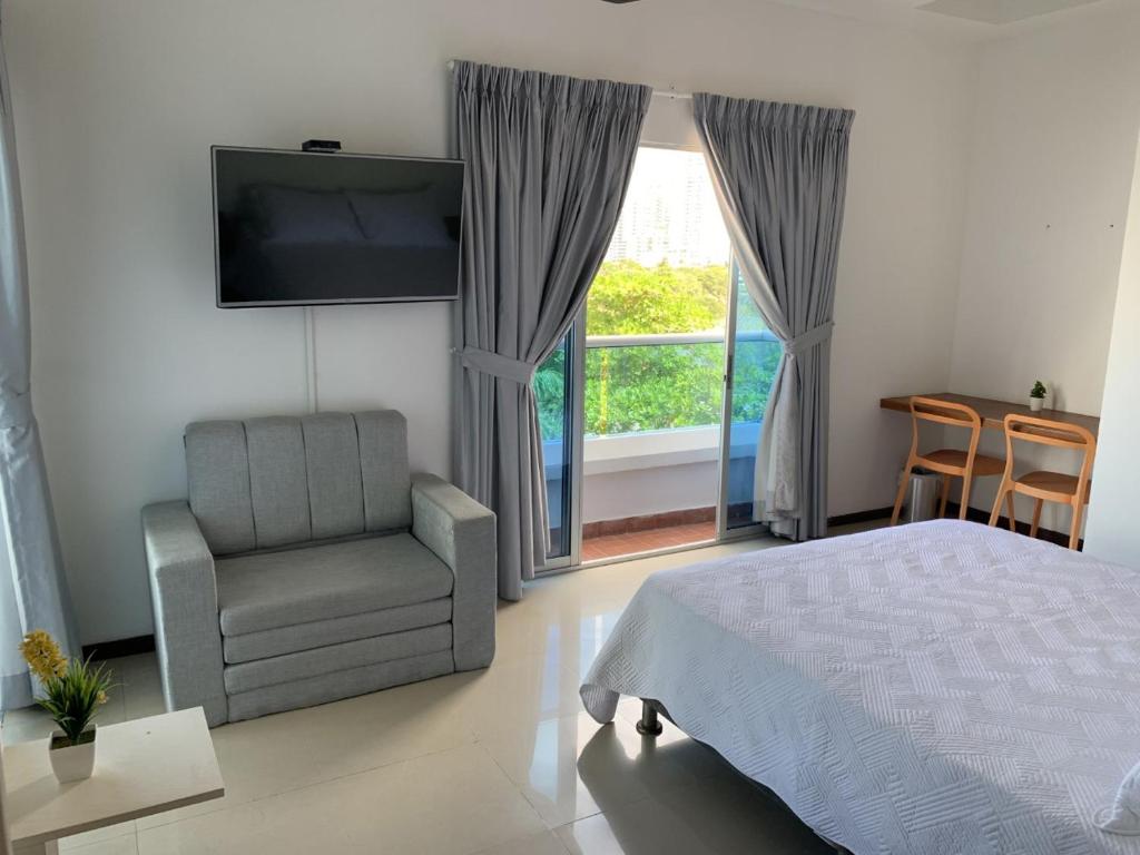 une chambre avec un lit, une chaise et une fenêtre dans l'établissement Hermoso y amplio apartamento en Cartagena de Indias, à Carthagène des Indes