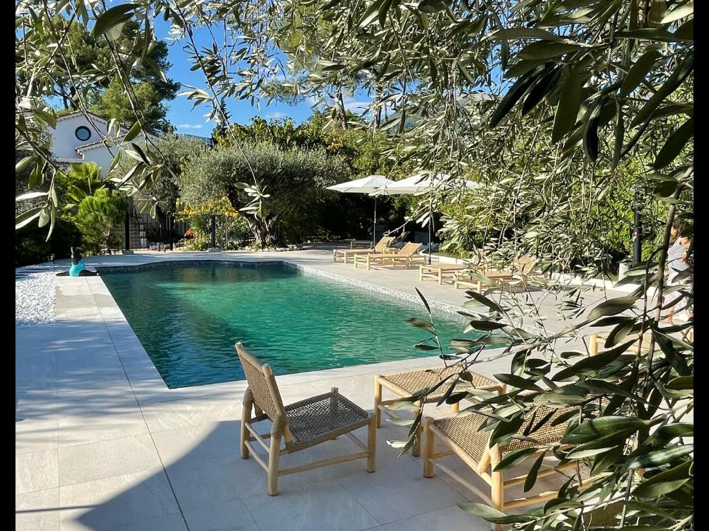 a swimming pool with two chairs and a table at Villa La Carpenée in Roquefort-les-Pins