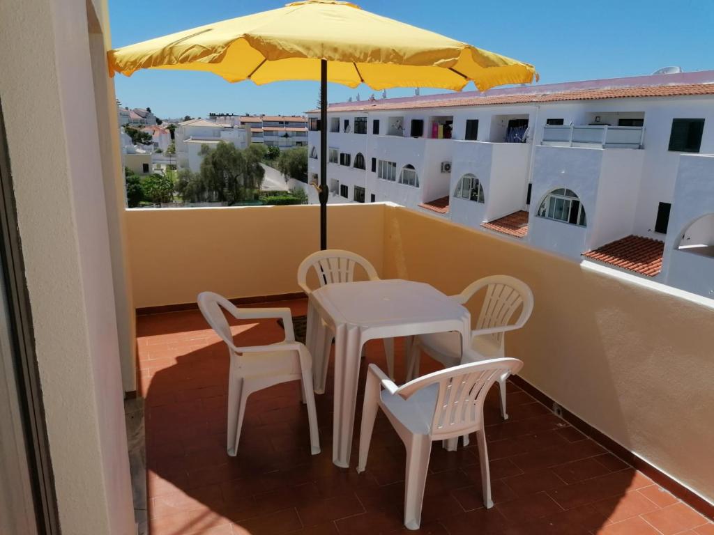 a table and chairs on a balcony with an umbrella at AAM jr in Albufeira