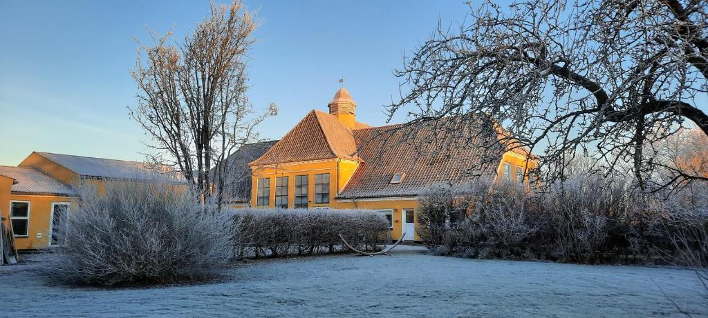 una gran casa amarilla con un patio cubierto de nieve en Børglum Mejeri Hotel, en Børglum