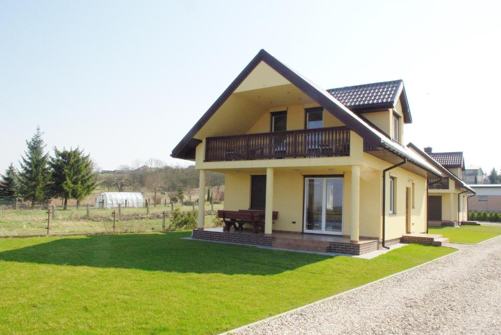żółty dom z balkonem na zielonym trawniku w obiekcie Nad Biebrzą Wojciech Bielawski w mieście Goniadz