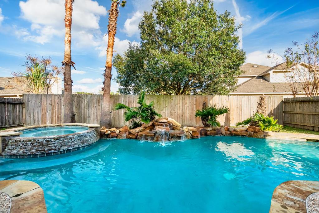 - une piscine avec une cascade dans une cour avec une clôture dans l'établissement Perfect Getaway with POOL, SPA, and Private Gym, à Spring