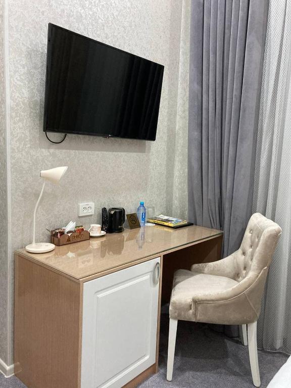 a desk with a chair and a television on a wall at Reikartz Amirun Tashkent in Tashkent