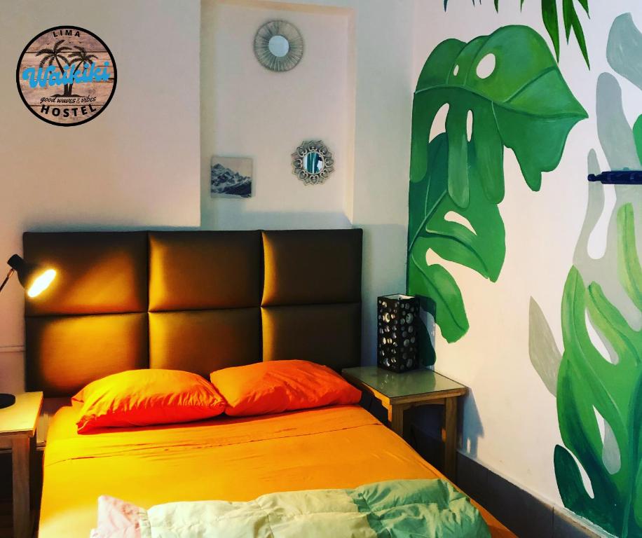 Waikiki Hostel في ليما: غرفة نوم مع سرير مع اللوح الأمامي من البرتقال