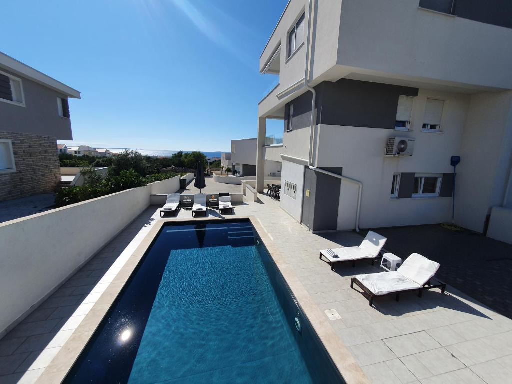 a swimming pool with lounge chairs and a building at Seastar Luxury apt with PRIVATE POOL and sea view in Novalja