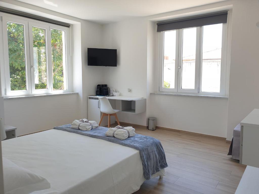 a white bedroom with a bed and a desk and windows at La Casa di Antonio Rooms in Palinuro