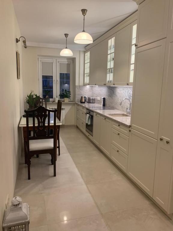 a kitchen with white cabinets and a table and a chair at Apartament Prestige Pruszków in Pruszków