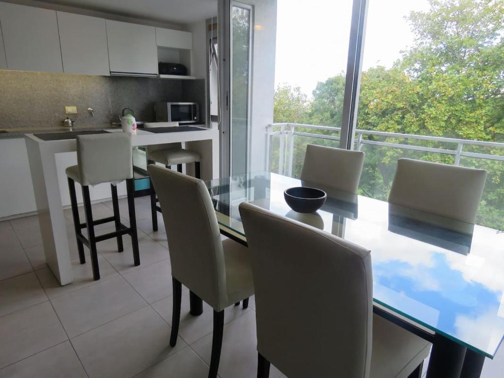 a kitchen and dining room with a glass table and chairs at Espectacular Departamento Playa Grande/Golf Club Cochera Vista Moderno in Mar del Plata