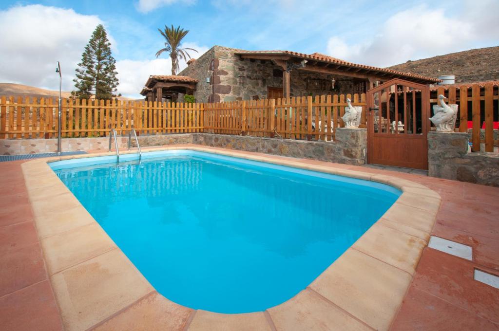 una piscina en un patio trasero con una valla de madera en La Bella Tuineje en Tuineje