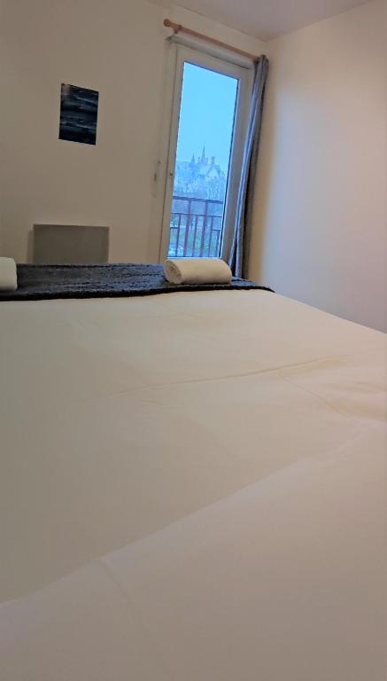 un lit blanc dans une chambre avec une fenêtre dans l'établissement LE BACO-BACO, FACE AU CHÂTEAU, AVEC PARKING, à Nantes