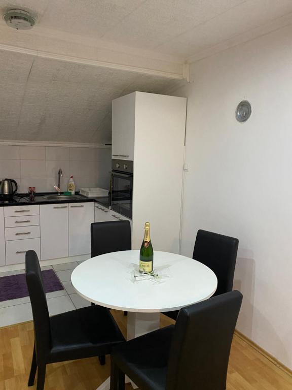eine weiße Küche mit einem weißen Tisch und einer Flasche Champagner in der Unterkunft Apartmani Petra in Novi Sad