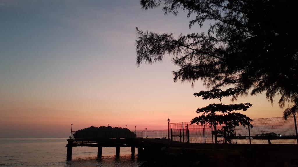 a dock in the water with a sunset in the background at PD Batu 9 Cocobay apartment with family in Kampong Tanah Merah