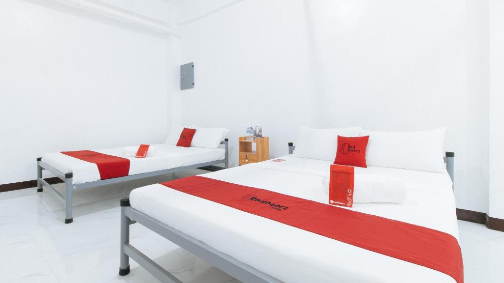 2 Betten in einem Zimmer mit roter und weißer Bettwäsche in der Unterkunft RedDoorz @ Catalina Pension House in Balingasag