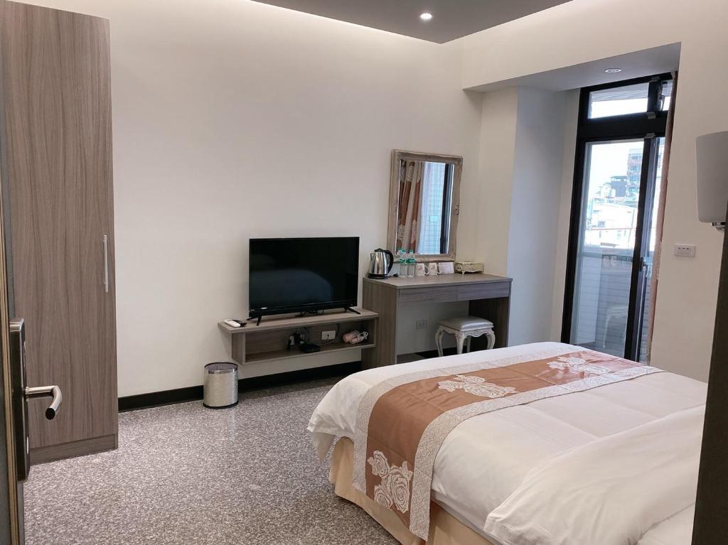 um quarto com uma cama e uma televisão de ecrã plano em Jin Zhan Hotel em Jincheng