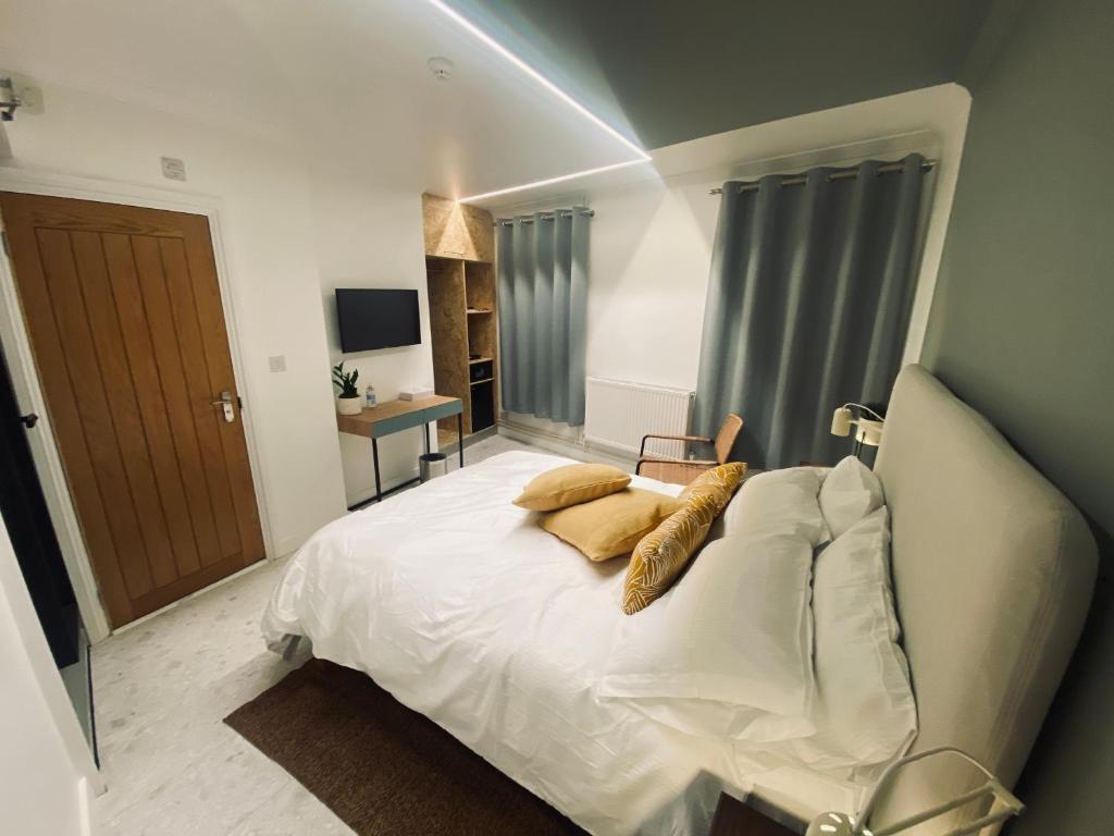 una camera da letto con letto, lenzuola e cuscini bianchi di Station Rooms a Winchester