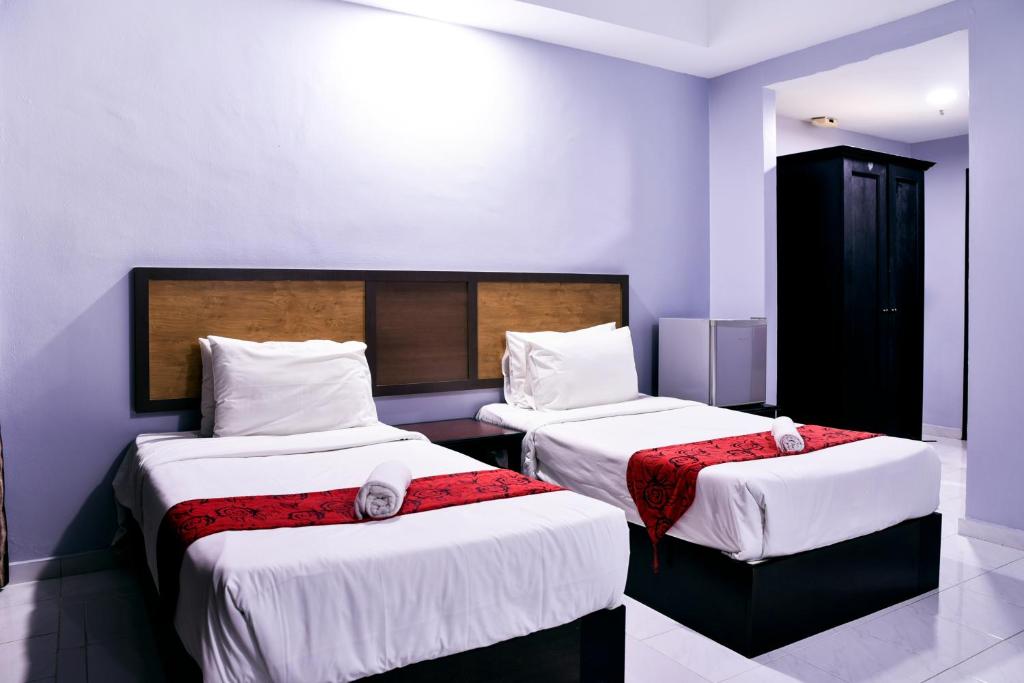 a bedroom with two beds with white sheets and red blankets at Leisure Cove Hotel and Apartments in George Town