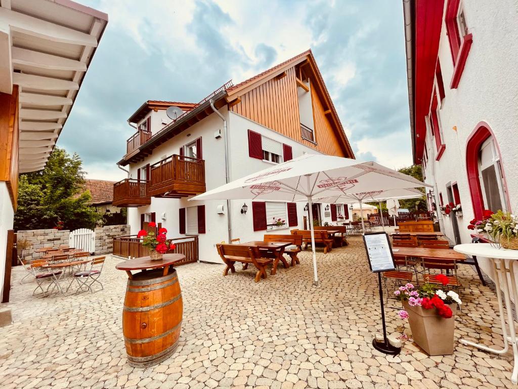 eine Terrasse mit Tischen und Sonnenschirmen sowie ein Gebäude in der Unterkunft Landgasthof Linde Hepbach, Hotel & Restaurant in Markdorf
