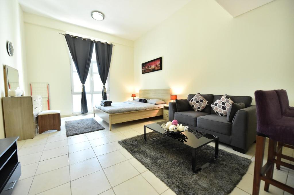 a living room with a couch and a table at Spacious Fully Furnished Studio Apt - Next to Metro, 5 Mins from Mall - TNY in Dubai