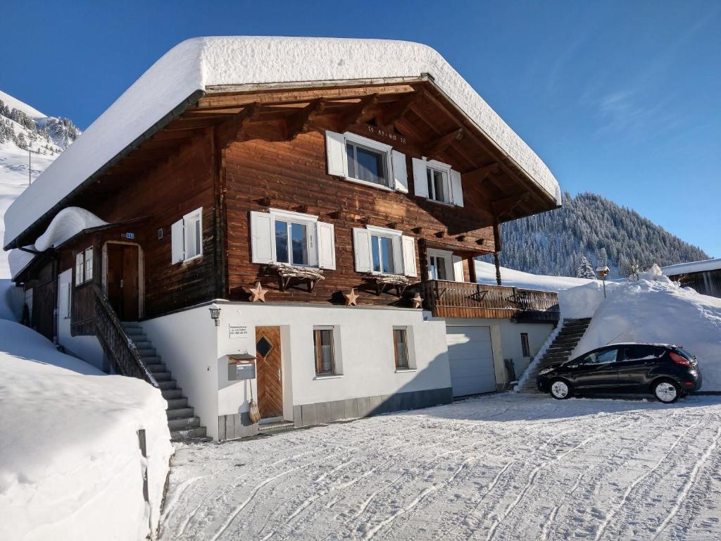 ein Auto, das vor einem Haus im Schnee parkt in der Unterkunft Studio Schija in St. Antönien