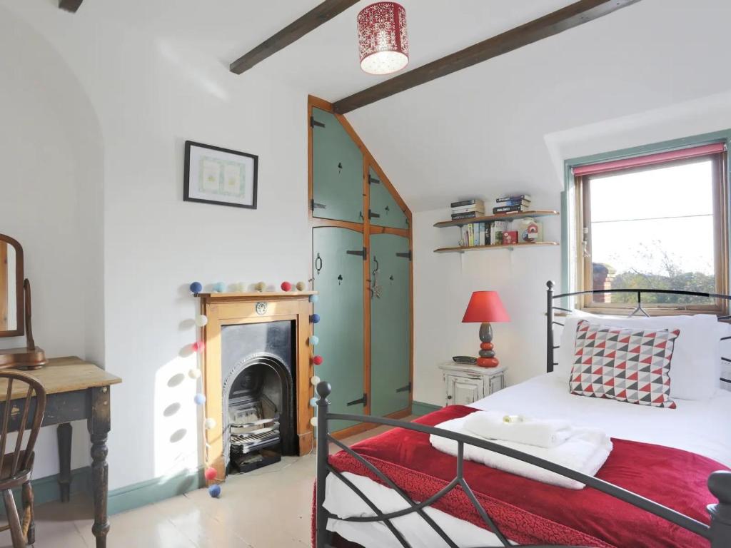 een slaapkamer met een bed en een open haard bij Piglet Cottage. A well equipped home from home. in Uggeshall