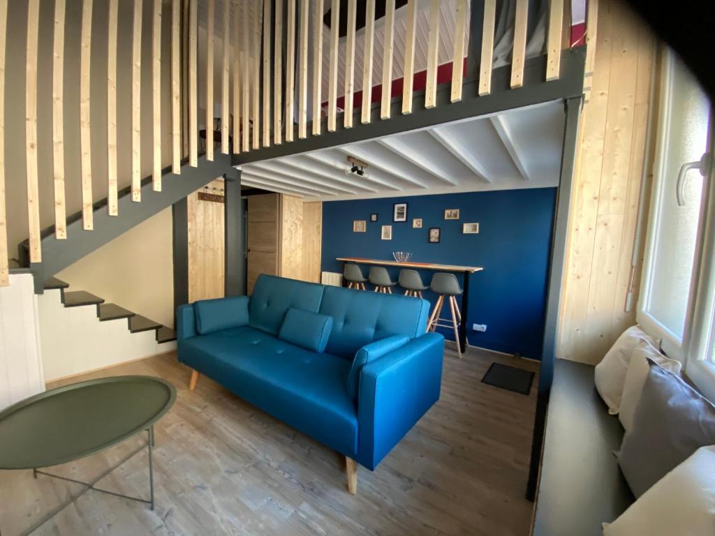 een woonkamer met een blauwe bank en een trap bij les Hallettes du havre hyper centre 300 de la mer in Le Havre