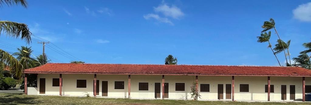 um edifício branco com telhado vermelho e palmeiras em Pousada Bouganville Bell em Salinópolis