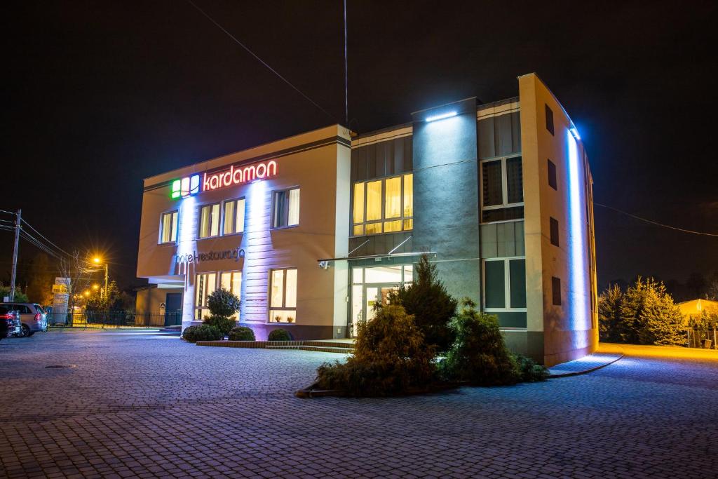 a hotel building with a neon sign in the night at Hotel Kardamon in Tarnów