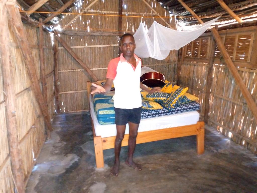 Un uomo in piedi accanto a un letto in una capanna di Povoado Bitonga a Inhambane