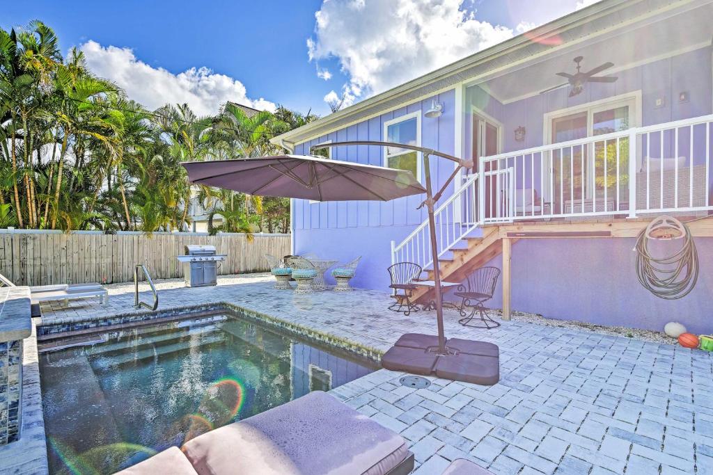 - une piscine avec un parasol à côté d'une maison dans l'établissement Anna Maria Island Escape, Walk to Beaches!, à Holmes Beach