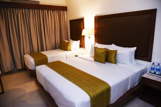 Habitación de hotel con 2 camas con almohadas amarillas en Lakshana Service Apartment - Big Temple Thanjavur en Thanjāvūr
