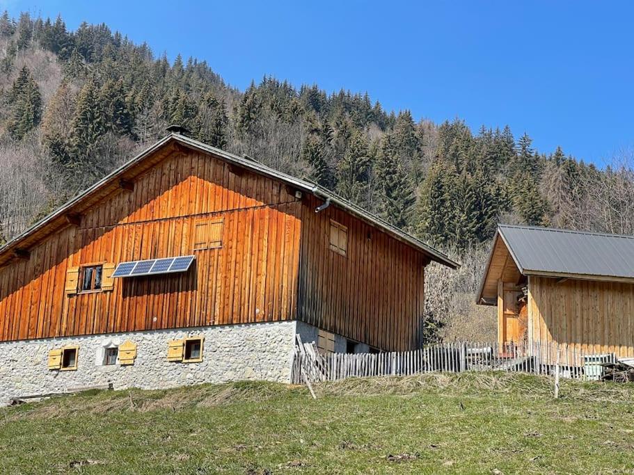 a large wooden barn with a fence in a field at Chalet Alpage Proche Genève in Mégevette