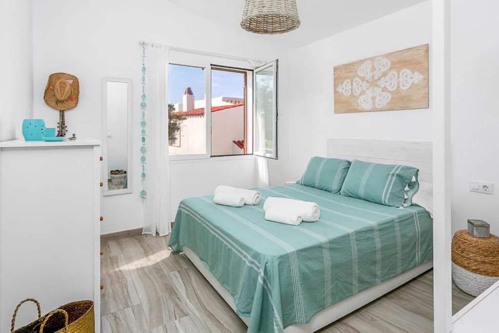 a bedroom with a bed with blue sheets and a window at Blue Moon in Cala en Bosc