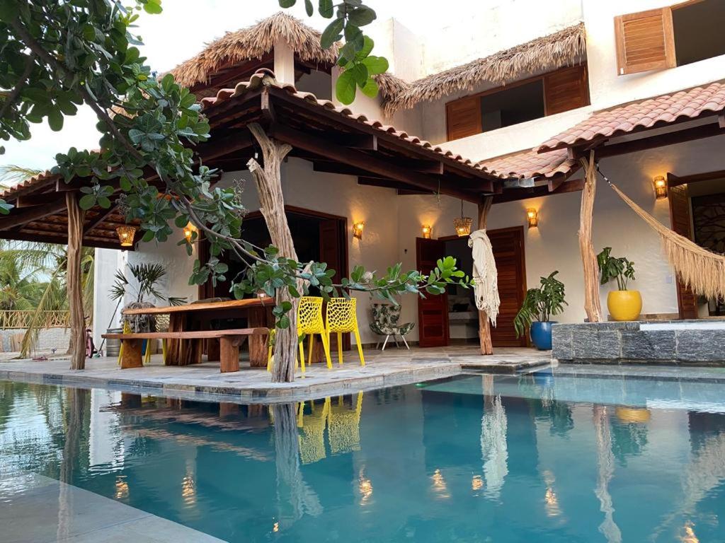 a house with a swimming pool in front of a house at Pousada Fortal Preá in Prea