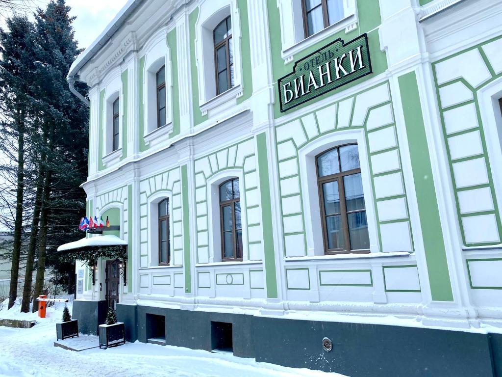 un edificio verde y blanco con un cartel en él en Отель «БИАНКИ», en Velikiy Novgorod