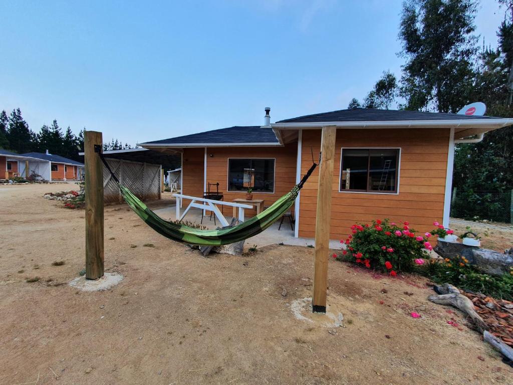 una casa con una hamaca delante de ella en Cabañas Olas del Bosque, en Pichilemu